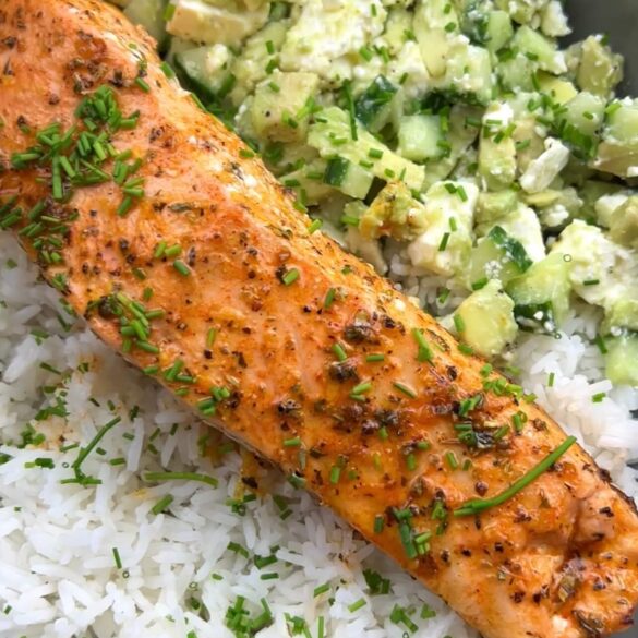 Gebratenes Lachs Filet auf Reis, daneben ein Salat aus Gurke, Avocado und Feta
