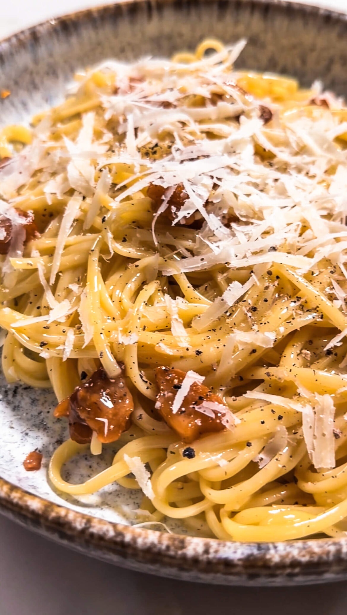 Ein Teller voller Nudeln mit Carbonara, Speck und geriebenen Parmesan